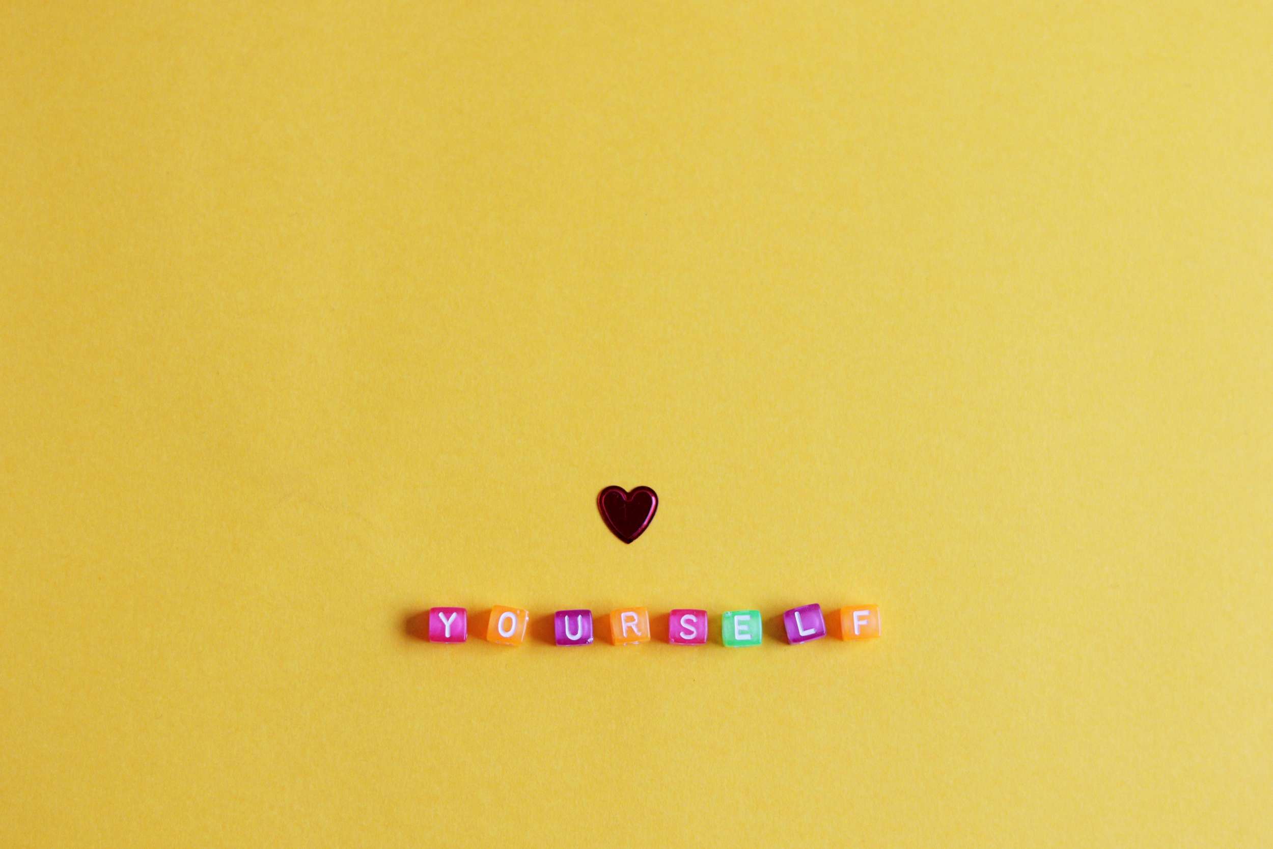 Colorful letter blocks spelling YOURSELF with heart above representing 5 minute self-love rituals